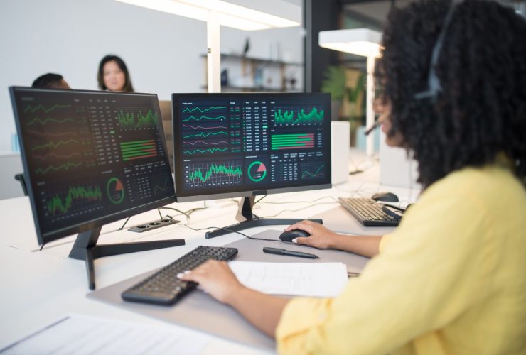 une personne avec 2 écrans qui analyse des stats