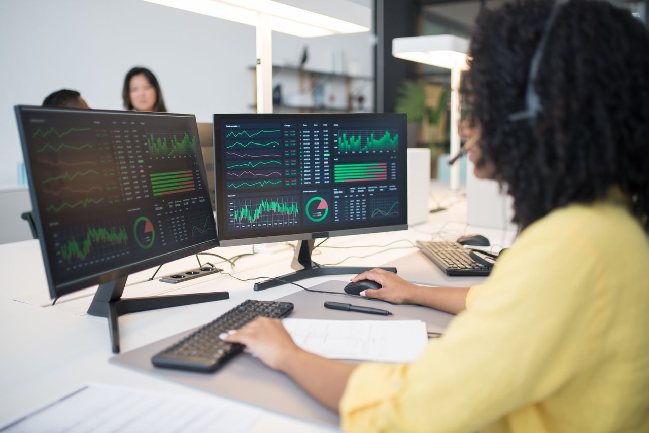 une personne avec 2 écrans qui analyse des stats